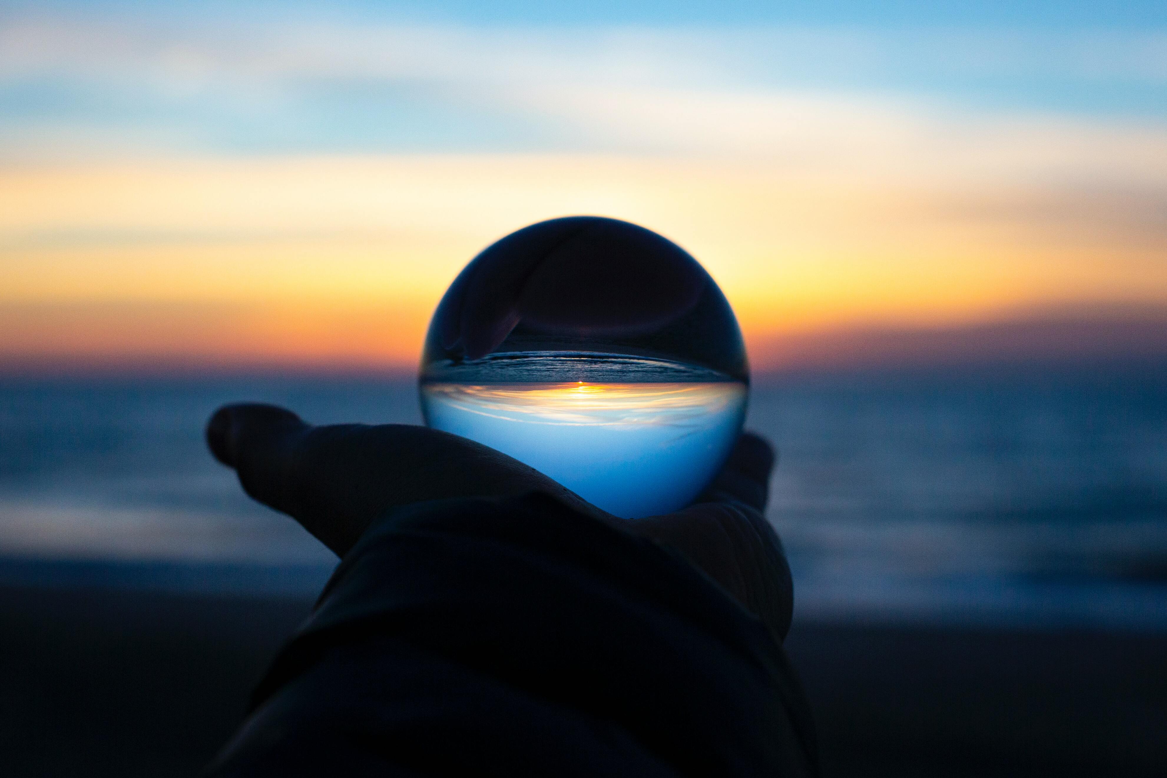 Hand holding a crystal ball on a beach